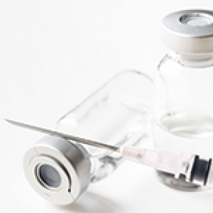 Stock image of empty vials and an uncapped syringe with needle